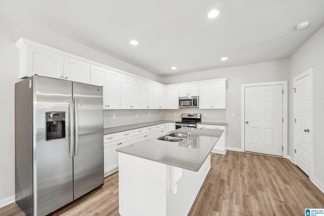 kitchen with white cabinetry, a center island with sink, light wood-type flooring, and appliances with stainless steel finishes