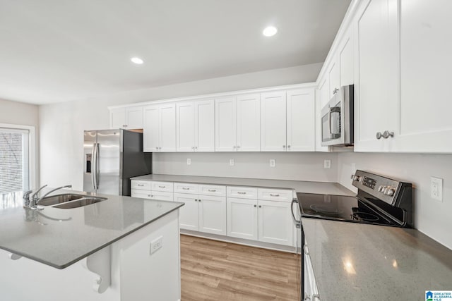 kitchen with appliances with stainless steel finishes, light wood-type flooring, sink, stone countertops, and white cabinets