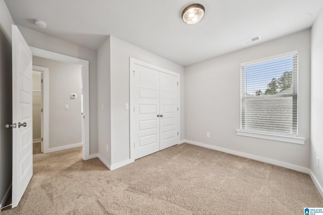 unfurnished bedroom with light carpet and a closet