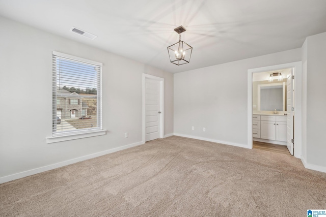 spare room with a notable chandelier, sink, and light carpet