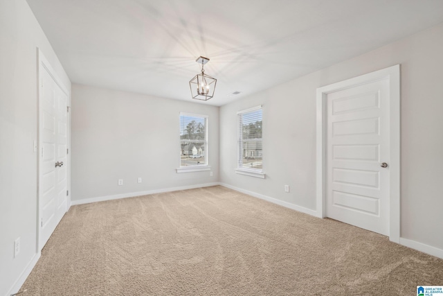 spare room with carpet and a chandelier