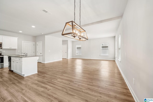 kitchen featuring white cabinets, a center island with sink, dishwasher, light hardwood / wood-style floors, and hanging light fixtures