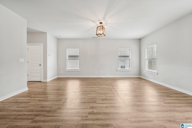 unfurnished living room featuring a chandelier and light wood-type flooring