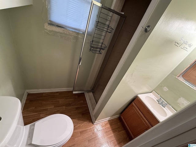 bathroom with wood-type flooring, vanity, toilet, and walk in shower