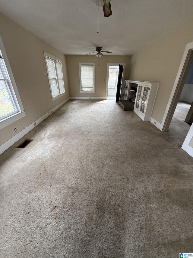 unfurnished living room featuring carpet, a wealth of natural light, and ceiling fan