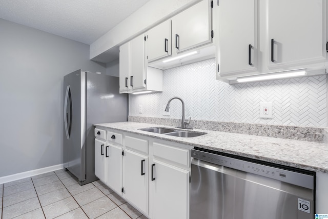 kitchen featuring tasteful backsplash, stainless steel appliances, sink, light tile patterned floors, and white cabinets