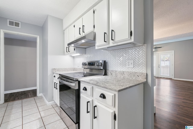 kitchen featuring white cabinetry, light hardwood / wood-style flooring, a textured ceiling, stainless steel electric stove, and decorative backsplash