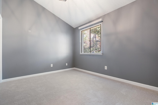 carpeted empty room with vaulted ceiling