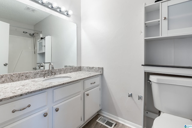 bathroom with vanity, a textured ceiling, a shower, wood-type flooring, and toilet