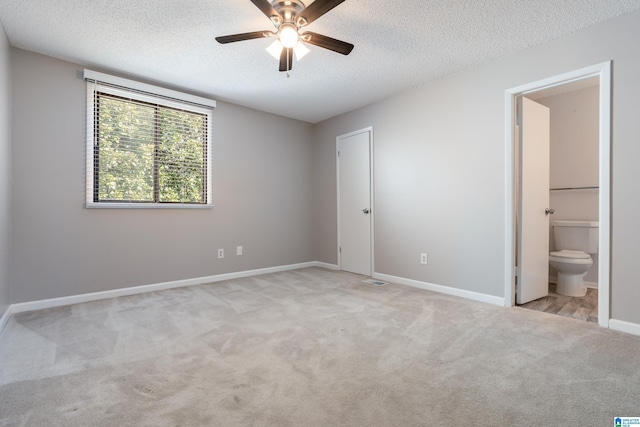 unfurnished bedroom featuring connected bathroom, ceiling fan, light colored carpet, and a textured ceiling