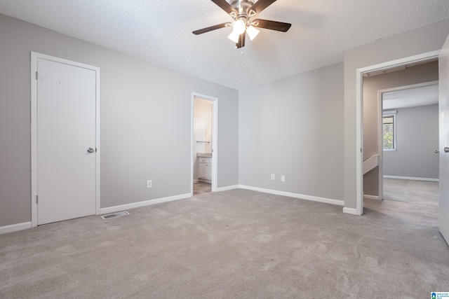 unfurnished bedroom featuring light carpet, a textured ceiling, and ceiling fan