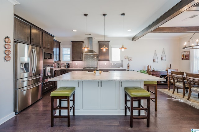 kitchen with wall chimney exhaust hood, a wealth of natural light, stainless steel appliances, and decorative light fixtures