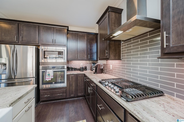 kitchen with wall chimney exhaust hood, tasteful backsplash, light stone counters, dark hardwood / wood-style flooring, and appliances with stainless steel finishes