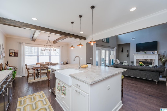 kitchen with pendant lighting, a center island with sink, light stone countertops, dark hardwood / wood-style flooring, and white cabinetry