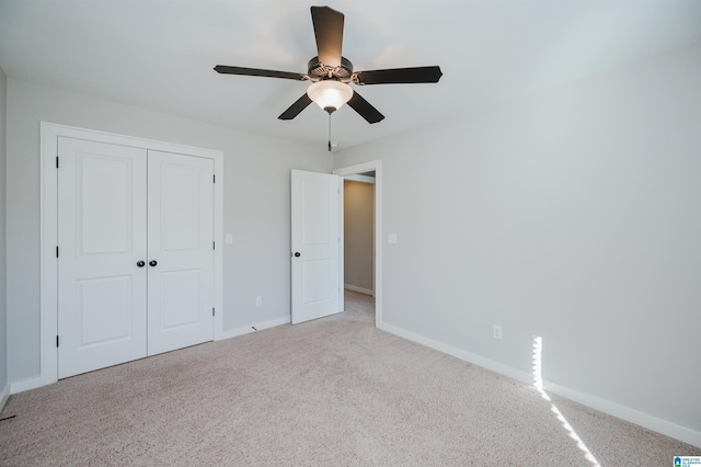 unfurnished bedroom featuring a closet, light colored carpet, and ceiling fan