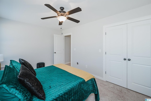 bedroom with ceiling fan, light carpet, and a closet