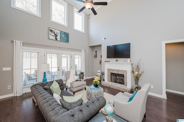 living room featuring french doors, a fireplace, dark hardwood / wood-style floors, and a high ceiling