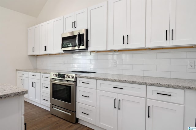 kitchen featuring dark wood-type flooring, vaulted ceiling, stainless steel appliances, and white cabinets