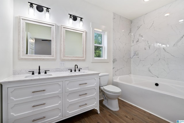 full bathroom featuring vanity, tiled shower / bath, wood-type flooring, and toilet