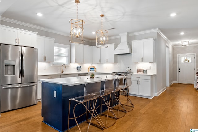 kitchen with appliances with stainless steel finishes, custom range hood, light hardwood / wood-style flooring, a center island, and white cabinetry