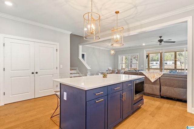 kitchen featuring light wood-type flooring, a breakfast bar, hanging light fixtures, a center island, and stainless steel microwave