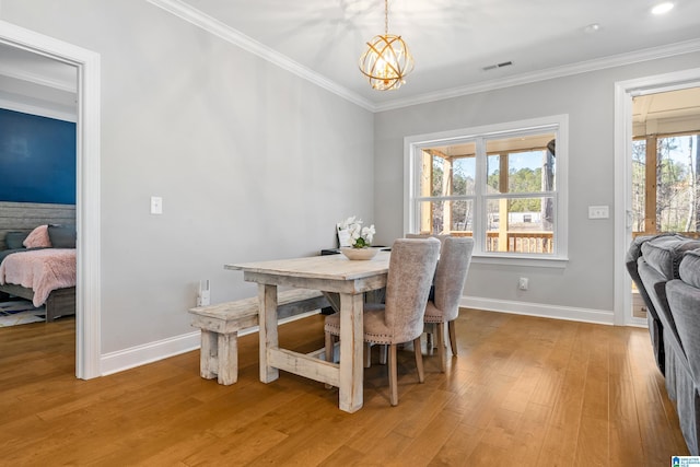 dining area with light hardwood / wood-style floors, crown molding, and a chandelier