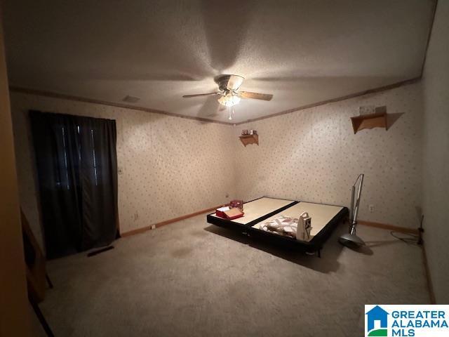 unfurnished bedroom with ceiling fan, carpet, and a textured ceiling