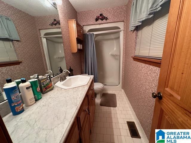 bathroom with a shower with curtain, tile patterned floors, a textured ceiling, toilet, and vanity