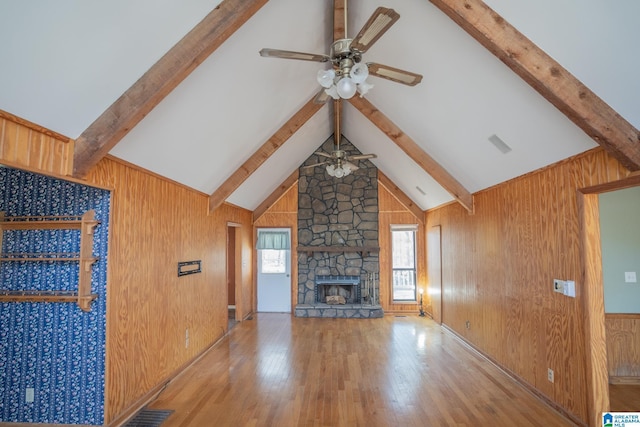 unfurnished living room featuring ceiling fan, a fireplace, hardwood / wood-style floors, vaulted ceiling with beams, and wood walls