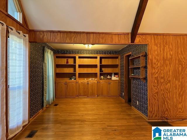 wine cellar with lofted ceiling with beams, light hardwood / wood-style floors, and wood walls