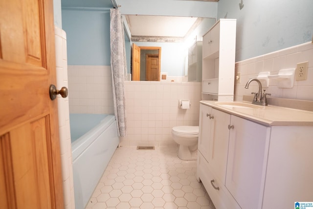 bathroom with tile patterned flooring, vanity, toilet, and tile walls