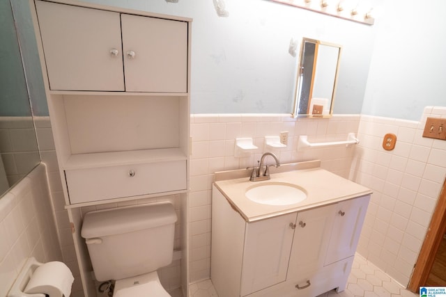 bathroom with tile patterned floors, vanity, toilet, and tile walls