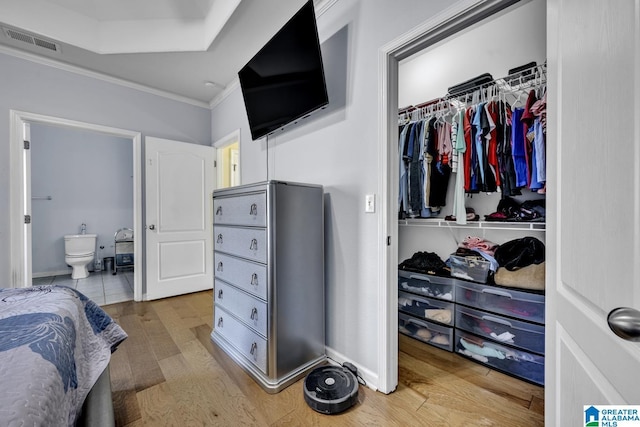 bedroom with hardwood / wood-style flooring, ornamental molding, and a closet