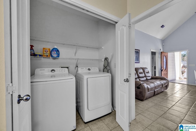 laundry room featuring light tile patterned floors, a towering ceiling, and washing machine and clothes dryer