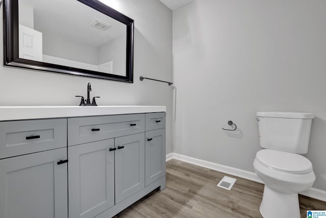 bathroom with hardwood / wood-style floors, vanity, and toilet