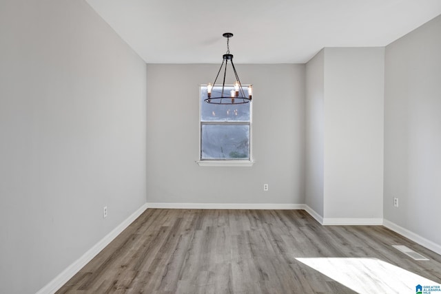 unfurnished room featuring a notable chandelier and light hardwood / wood-style floors