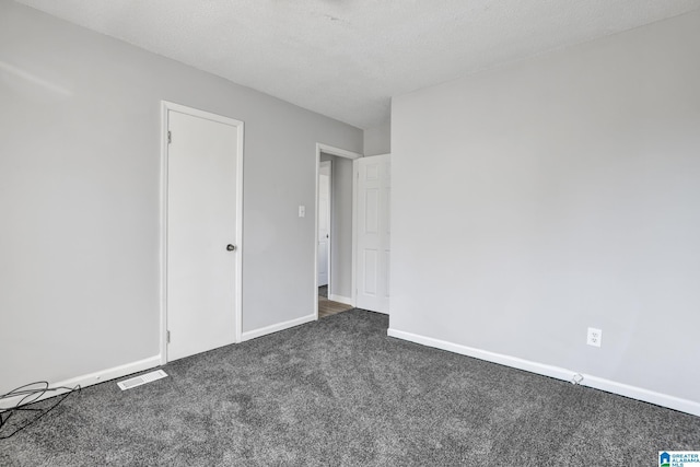 unfurnished bedroom with a textured ceiling and dark carpet