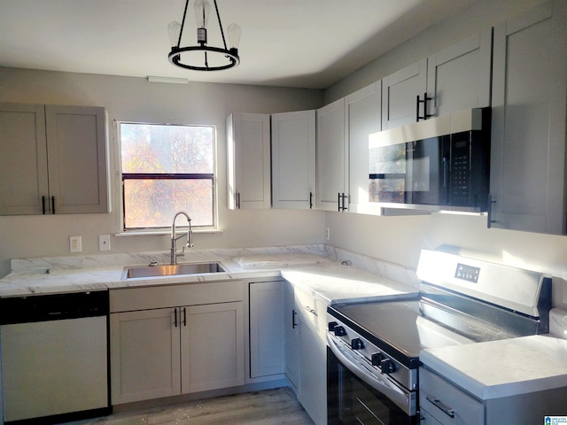 kitchen with decorative light fixtures, light wood-type flooring, stainless steel appliances, and sink