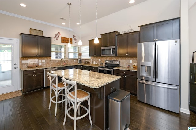 kitchen featuring dark wood-type flooring, a kitchen island, hanging light fixtures, and appliances with stainless steel finishes