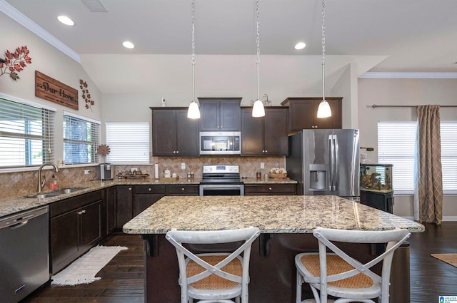 kitchen featuring sink, a center island, dark hardwood / wood-style flooring, decorative light fixtures, and appliances with stainless steel finishes