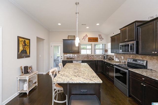 kitchen with decorative backsplash, appliances with stainless steel finishes, decorative light fixtures, a kitchen island, and dark hardwood / wood-style flooring