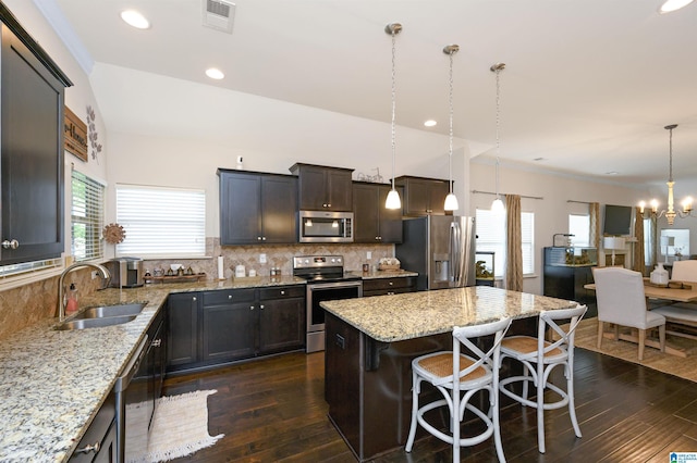 kitchen with stainless steel appliances, sink, decorative light fixtures, a notable chandelier, and a center island