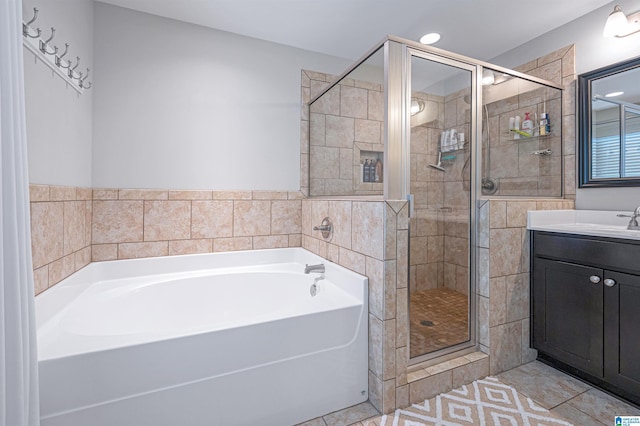 bathroom with tile patterned flooring, vanity, separate shower and tub, and tile walls