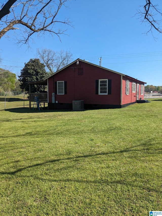 view of side of property with central AC unit and a yard