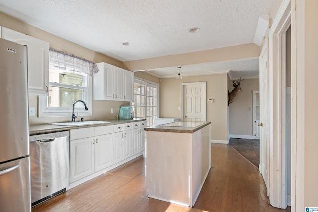 kitchen featuring appliances with stainless steel finishes, a center island, light hardwood / wood-style flooring, and white cabinetry