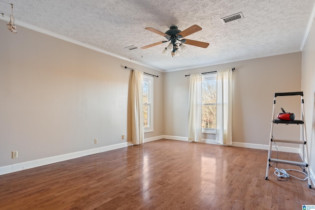 spare room with crown molding, wood-type flooring, and a textured ceiling