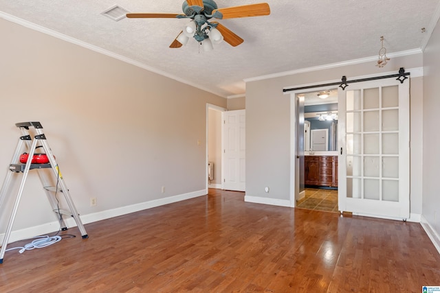 interior space with a barn door, crown molding, hardwood / wood-style floors, and a textured ceiling