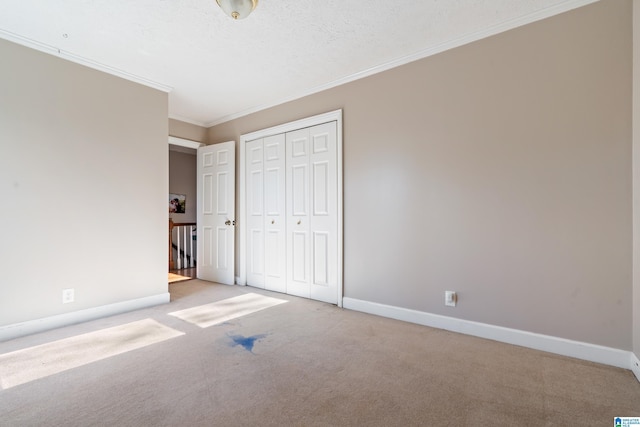 unfurnished bedroom featuring light colored carpet, ornamental molding, a textured ceiling, and a closet