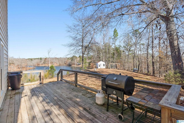 deck featuring a grill, a water view, and a storage shed