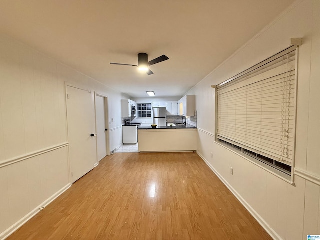 kitchen featuring stainless steel refrigerator, white cabinetry, ceiling fan, light hardwood / wood-style floors, and decorative backsplash